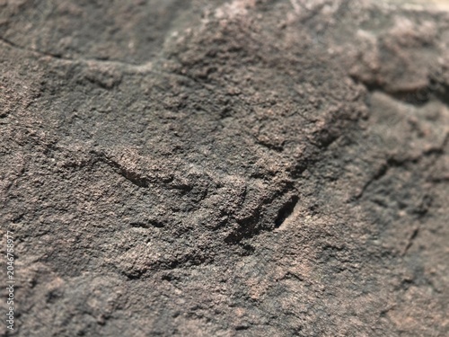 Schilderij op canvas Close-up texture of a rough dark stone surface, showing natural weathered rock details and gritty geological patterns