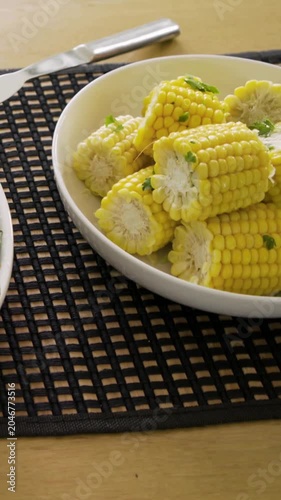 Vertical video: Panning camera showing corn bowl on table to reveal meal, with fork, glass, basket