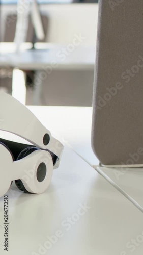 Vertical video: Panning shot showing VR headset side view in office, charts, stand and grey panel