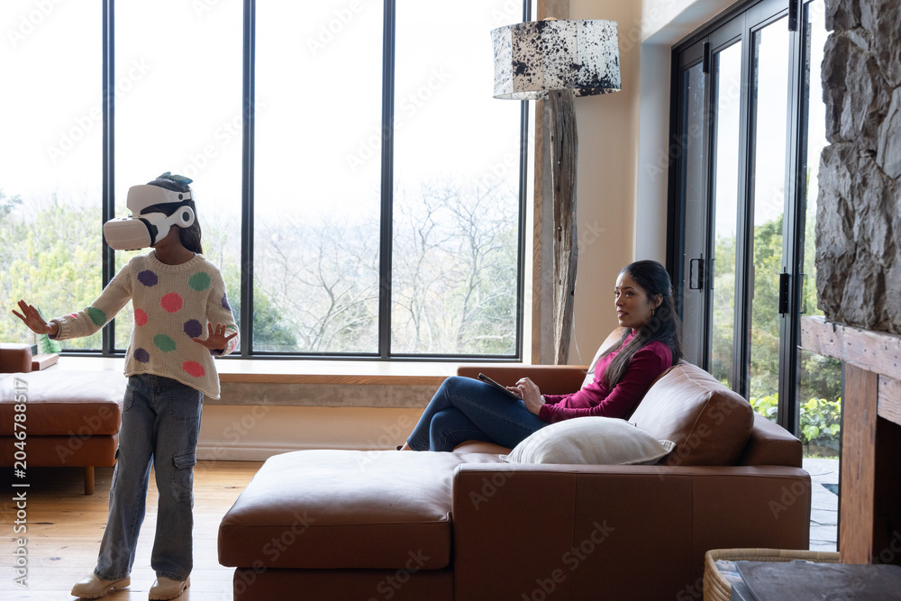 Obraz premium Mother and daughter playing with VR headset near windows, mother holding smartphone, copy space