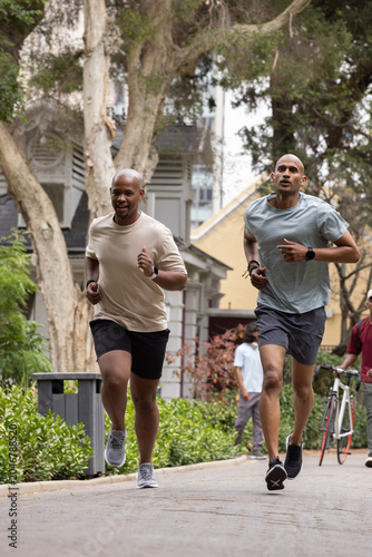 Fotografia African American men jogging together on tree-lined residential path wearing wat