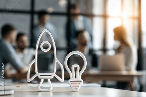 A modern startup workspace featuring a creative team brainstorming together. The foreground highlights a rocket and light bulb symbolizing innovation and ideas