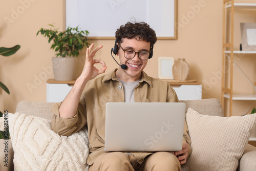 Young male online business consultant with headset and laptop video chatting ...