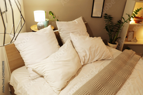 Cozy bed with glowing lamp ...