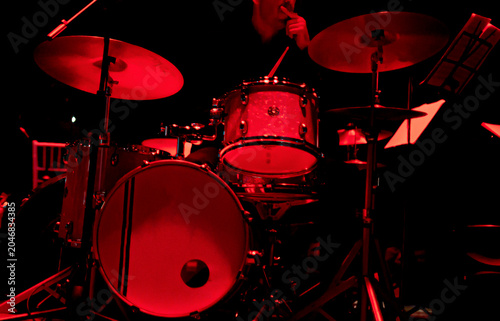 Jazz drum set illuminated in red stage light with copy space, Close-up of a jazz drum set under intense red stage lighting before a live performance. Dark background and large copy space create a dram