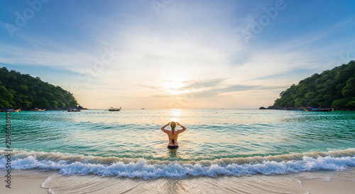 Man standing in turquoise ocean water at sunset, enjoying tropical beach vacation