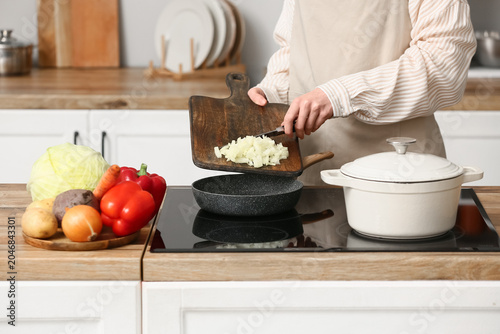 Young woman adding onion in...