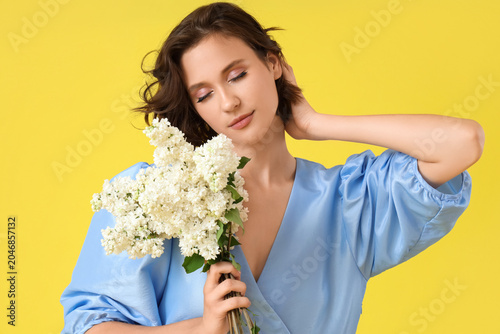 Beautiful young woman with bouquet of blooming white lilac flowers on yellow ...
