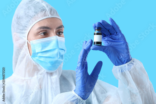 Female scientist with ampule on blue background, closeup