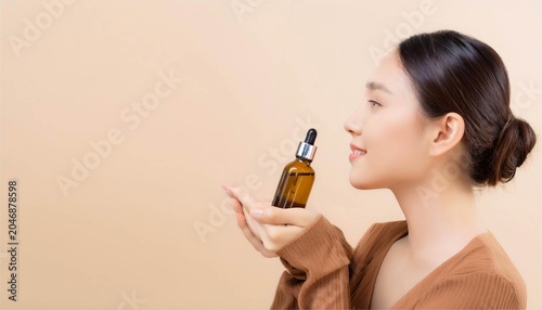Beautiful Japanese woman holding cosmetic serum bottle, wellness and relaxation concept with copy space