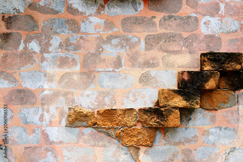 Cracked and weathered brick wall with uneven ledge and exposed bricks in rustic setting