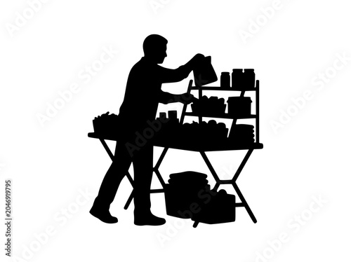 Silhouette of a man arranging items on a market stall table