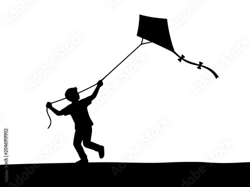 Silhouette of a young boy running and flying a kite outdoors