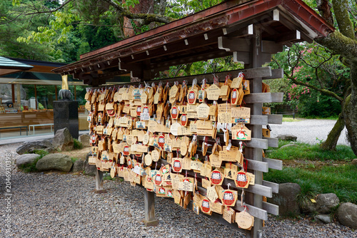 Ema Prayer Plaques and Daruma Wishes Hanging on Wooden Rack at Japanese Shrine