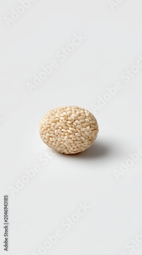 A spherical ball made of many individual grains of white sushi rice on a white background