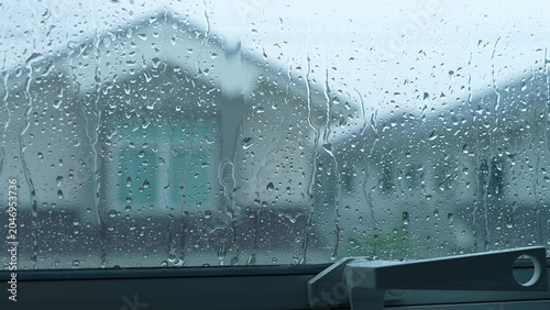 Фотография Raindrops streak down the glass, but the sealed window keeps the storm outside, reflecting on energy efficiency, climate adaptation, storm resilience, and the importance of secure housing