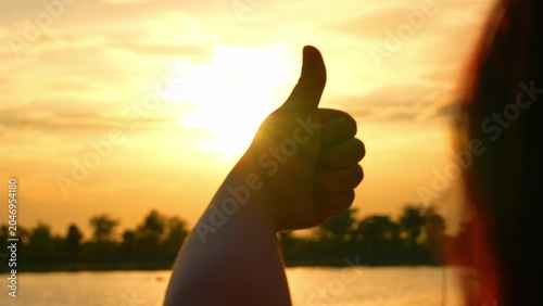 Foto A hand gives a thumbs-up against a golden sky, symbolizing approval and positivity