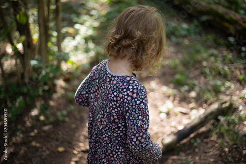 Child alone in a sunny forest. Girl alone in the forest. Contrast shot of a child in nature.