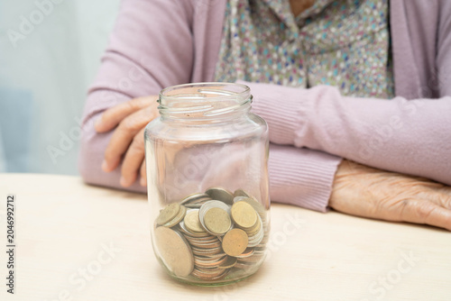 Retired Asian elderly woman counting coins money and worry about monthly expenses and treatment fee payment.