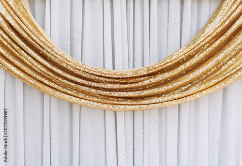 Gold curtains against a white background, in ripples.