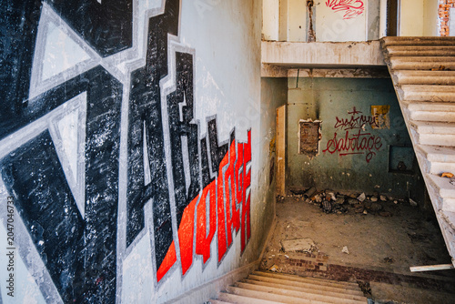 Graffiti-covered staircase inside the abandoned Savane Sanatorium in Tskaltubo, Georgia, blending urban art with Soviet-era decay. The grafiti says 