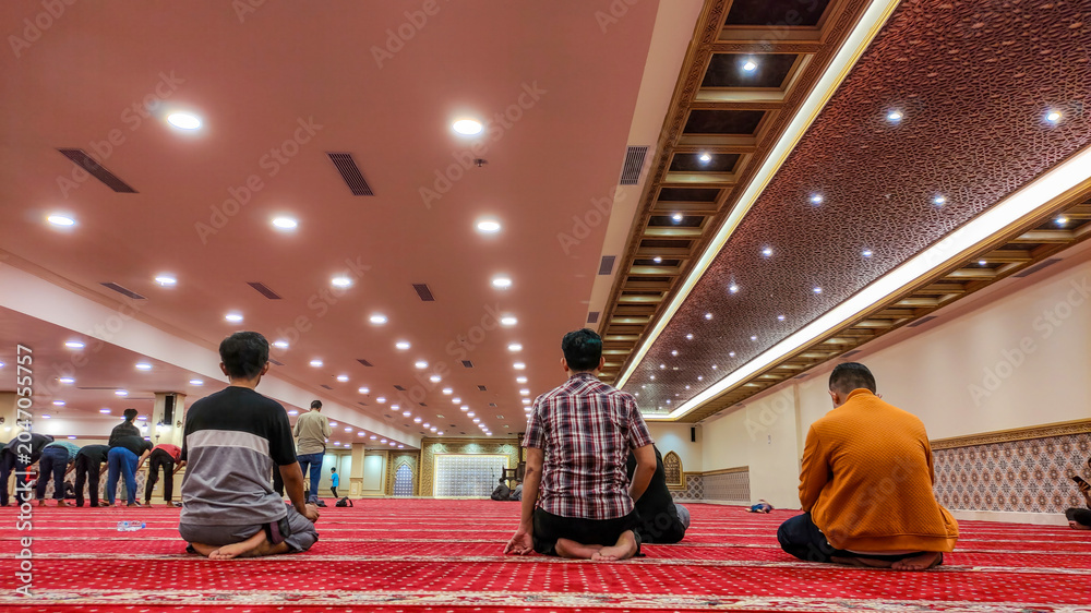 Obraz premium Men praying on a red carpet in a mosque