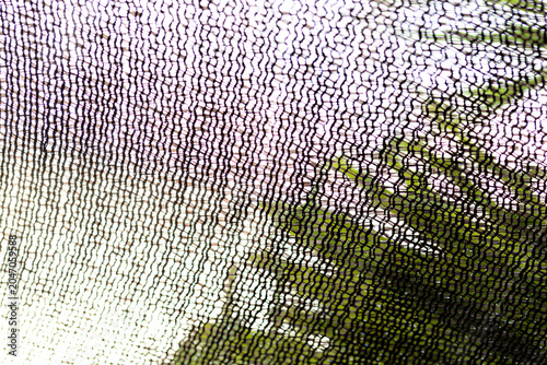 Fotografie Black plastic shading net texture background with bright backlight