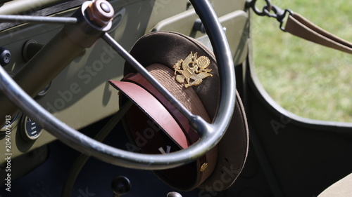 View of a vintage US Army officer service cap with a gold eagle emblem hanging on the steering wheel of an olive drab military vehicle La Ferte-Alais, Ile-de-France, France.