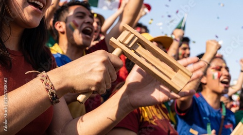 Vigorous motion of wooden noisemaker during daytime match celebration