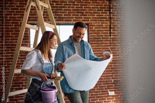 Foto Happy couple going through blueprints while working on home renovation