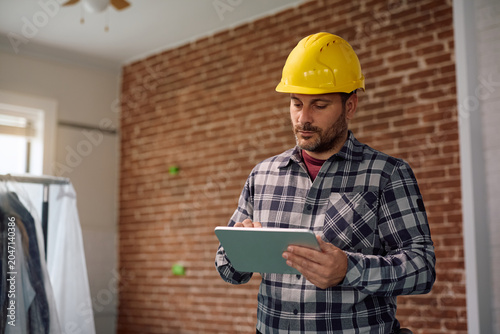 Tableau sur toile Manual worker working on touchpad during home remodeling project.
