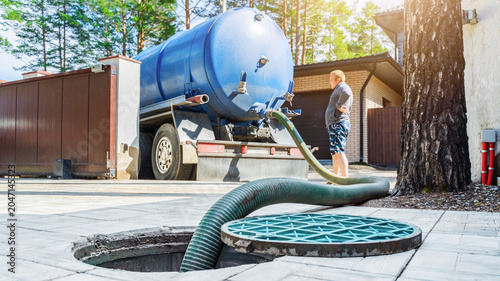 Tableau sur toile Septic tank service truck connected to sewage tank during daytime work in reside