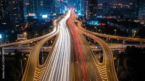 Aerial view of a lit highway interchange at night in a city.