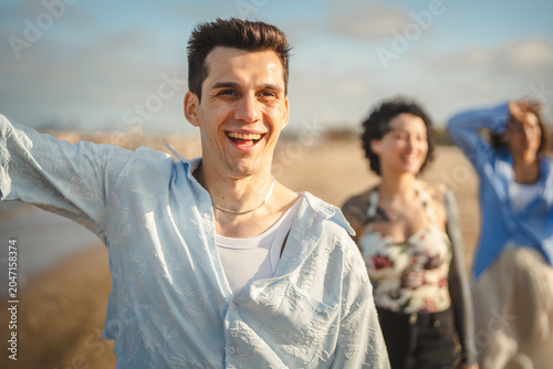 Canvastavla Young man smiling walking with friends on beach