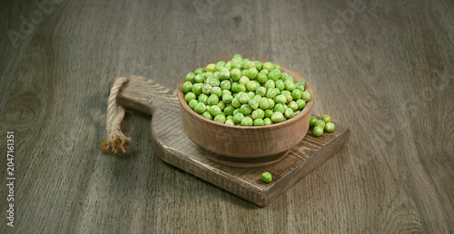 Photos Fresh green peas in a wooden bowl placed on rustic cutting board over wooden table background