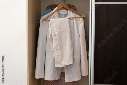 Tableau sur toile Elegant white women pantsuit with double breasted blazer and trousers hanging on