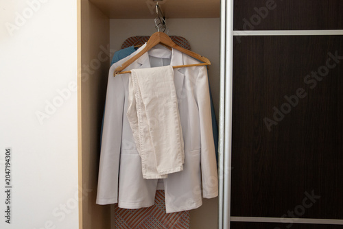 Photos Elegant white women pantsuit with double breasted blazer and trousers hanging on