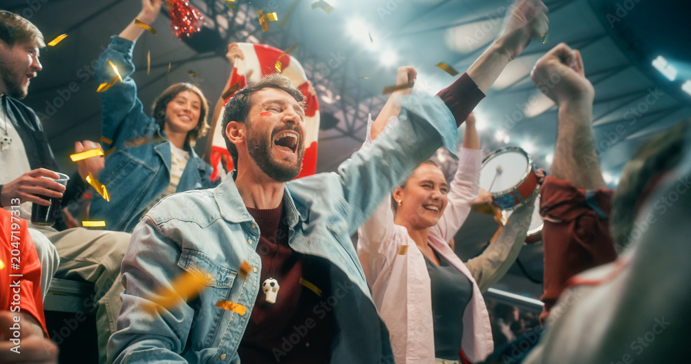 Obraz premium Energetic Portrait of Diverse Male and Female Soccer Football Fans in Championship Stadium, Arms Lifted for Happy Cheer, Smiling and Excited as Gold Confetti Flies During World Cup League Match.