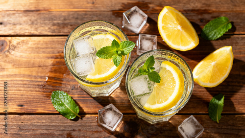 Top down flat lay of summer iced lemonade with mint on rustic wooden table copy space