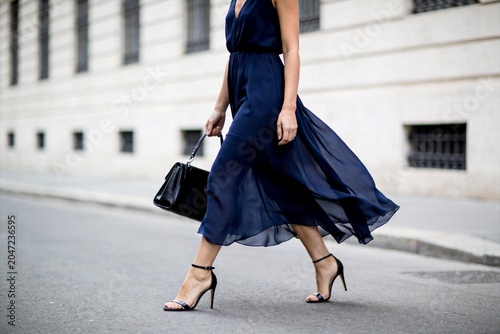 Woman in flowing blue dress walking street