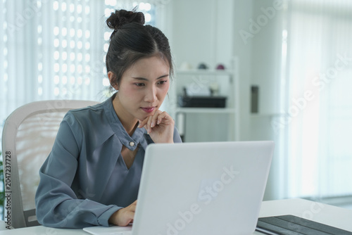 A professional businesswoman sitting at her office desk is working on her laptop and typing to communicate with success
