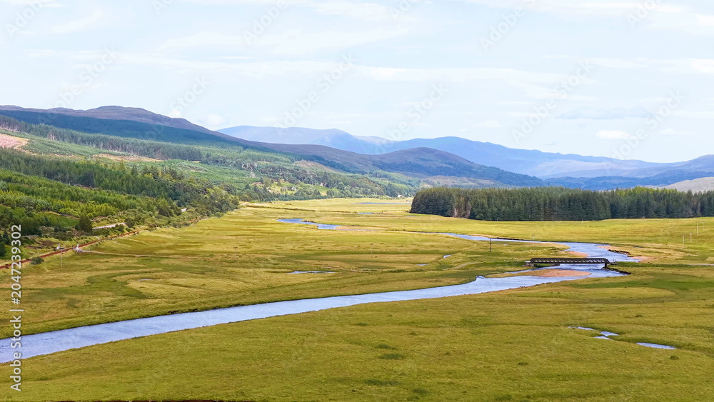 Naklejka premium Aerial View of a Winding River Through a Scottish Highland Valley