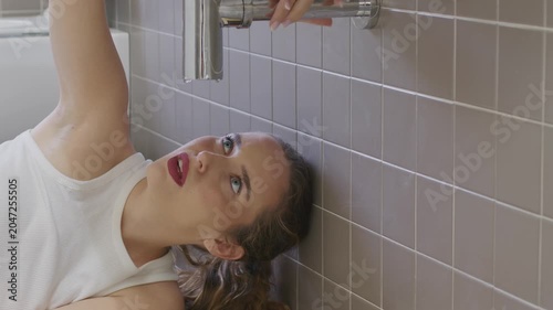 Worried young woman looking at leaking pipe under bathroom sink home emergency