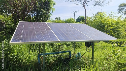 Solar panel array set up for off grid power in a lush green environment with blue sky overhead