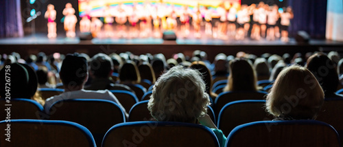 фотографія Audience sitting in theater rows watching performance on stage