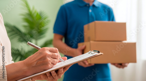 Delivery person hands over packages while recipient signs for them on clipboard