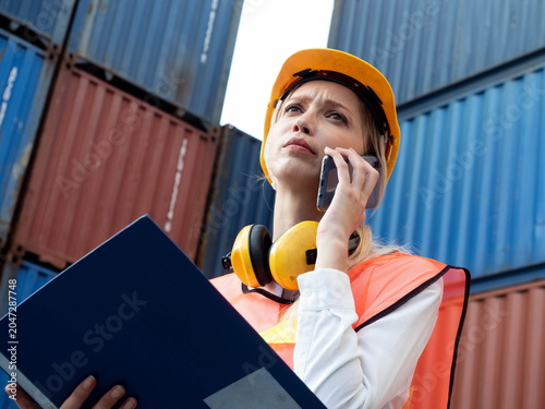 woman female lady talk speak mobile phone smartphone industry report paper file serious worry industry shipping profession warehouse control import export tax tariff shipping safety work job cargo