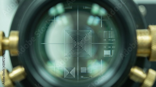 View through an optical lens showing precise alignment reticle patterns and concentric squares for semiconductor chip manufacturing process