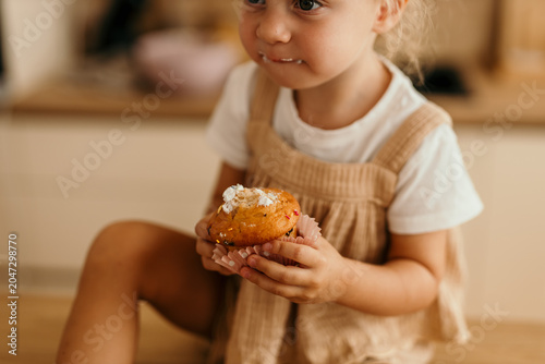 Canvas Print Toddler girl enjoying sweet muffin snack