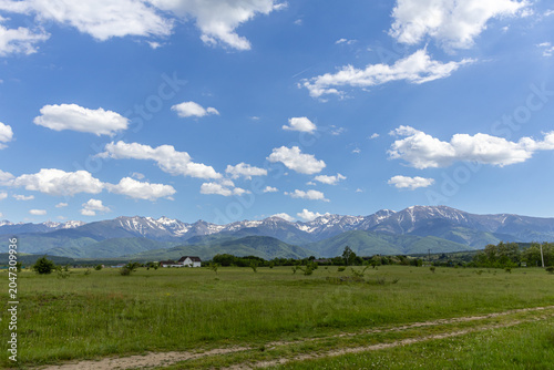 Scenic Mountain Range View with Country Dirt Road and Green Meadow